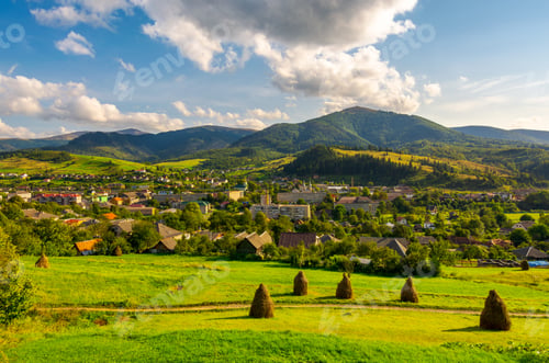 Preview: Beautiful Rural Landscape In Mountains. Haystacks On The Grassy Hills. Village At The Foot Of The