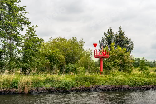 Preview: Orange-Red Radar Reflector Number 7 On The Banks Of A Wide Dutch River On A Cloudy Day At The