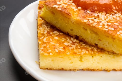 Preview: Slice Of Cheesecake With Sesame Seeds And Apricot Jam On A Black Background