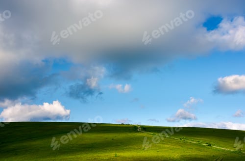 Preview: Grassy Hillside And Gorgeous Afternoon Cloudscape. Countryside Road Winds Uphill In To The