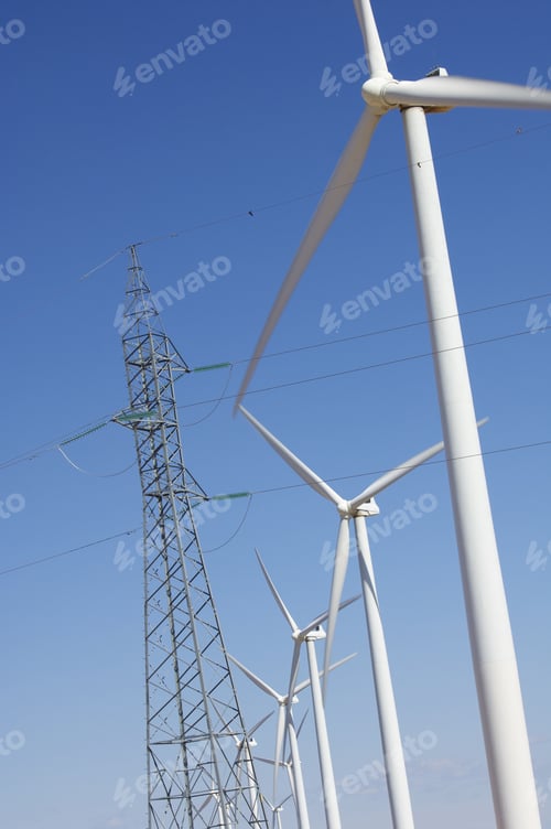 Preview: Windmills Aligned And Pylon With A Clear Blue Sky