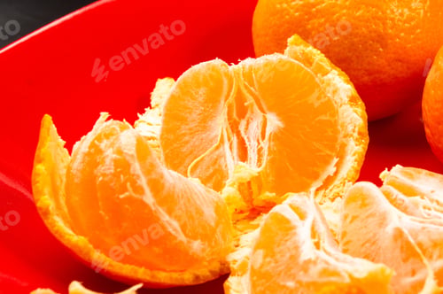 Preview: Tangerines, Peeled Tangerine And Tangerine Slices In A Red Plate On Black Background