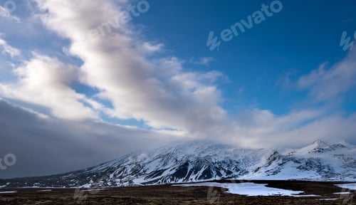 Preview: Icelandic Landscape With Mountains And Meadow Land Covered In Snow And Blue Cloudy Sky At