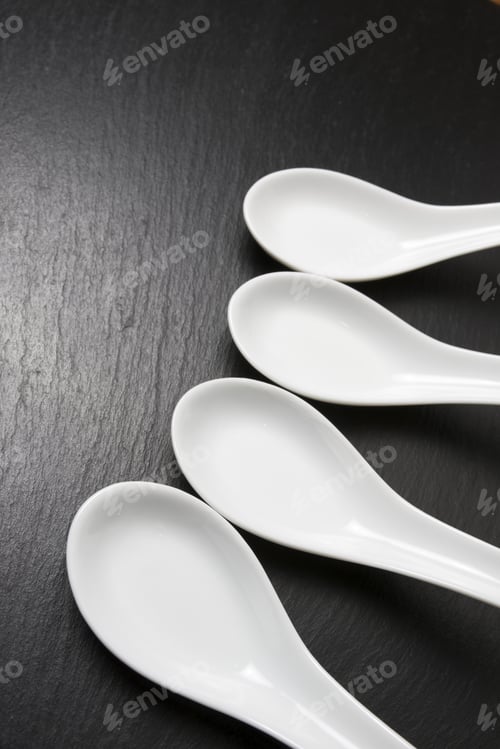 Preview: Four Small White Spoons On A Table Slate