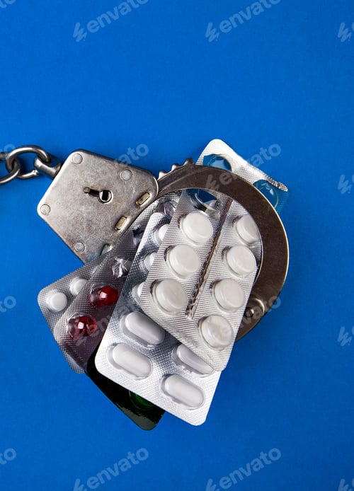 Preview: Pills In The Handcuffs On The Blue Paper Background Closeup
