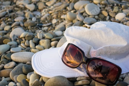 Preview: White Cap And Sunglasses On Pebble Beach, Sunset