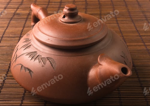 Preview: Brown Chinese Teapot Of Yixing Clay With Traditional Ornament On Bamboo Mat