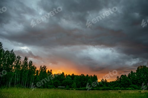 Preview: Contrast Rain Storm Clouds Over Green Meadow And Some Trees In Summer. Blue Sky Before The Rain
