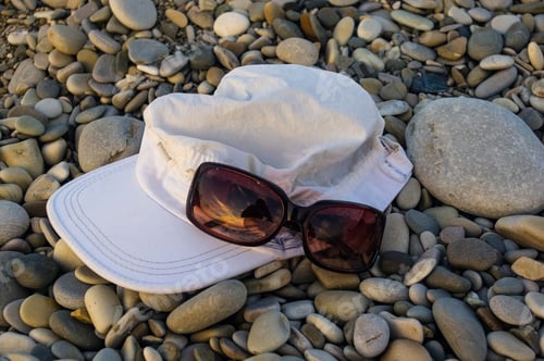 Preview: White Cap And Sunglasses On Pebble Beach, Sunset