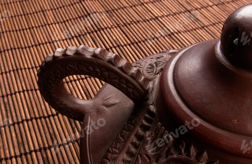 Preview: Brown Chinese Teapot Of Yixing Clay With Traditional Ornament On Bamboo Mat