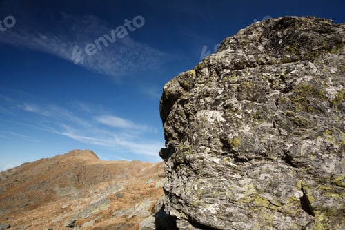 Preview: Rocky Mountains With Yellow-Brown Grass Under Blue Sky