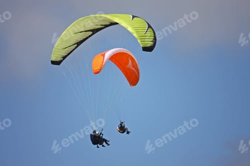 Paragliders soar through a clear blue sky
