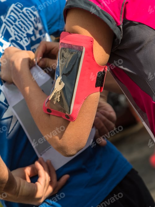 Preview: Girl With Smartphone Armband Case Fasten Bib Number To T-Shirt Before City Marathon