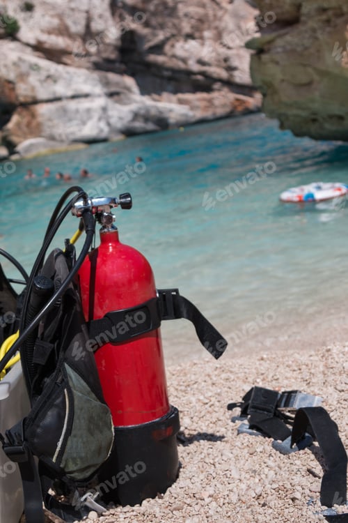 Preview: Red Scuba Oxygen Tank For Divers On A Beach, White Life Preserver On Sea In Background
