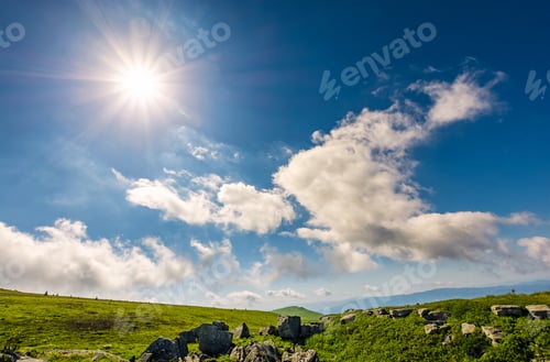 Preview: Sunburst On A Blue Sky With Clouds Over The Mountains With Rocky Hillside