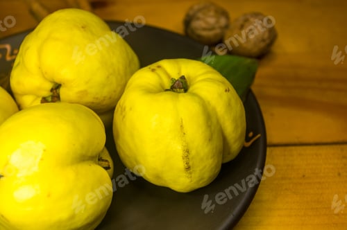 Preview: Large Yellow Quince Fruits On A Ceramic Plate, With Anise, Cinnamon, And Walnuts