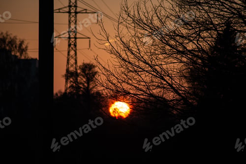 Preview: Red Sunset With Sun Setting Down Behind Large Electricity Power Line Metal Poles. Dark Silhouettes