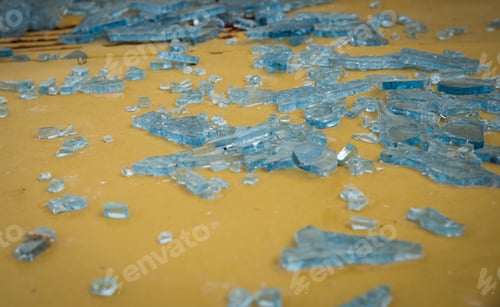Preview: Broken Blue Crystal Pieces Of Crystal Glass On A Yellow Metallic Surface.