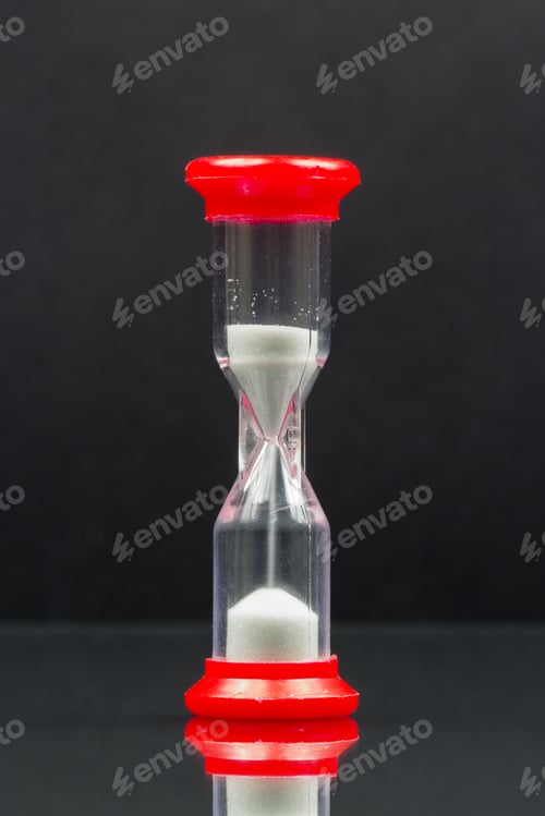 Preview: Small Red Hourglass With White Sand On Black Background With Reflexion