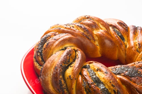Preview: Braided Poppy Seed Round Loaf In A Red Plate On White Background