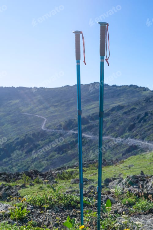 Preview: Pair Of Trekking Poles On The Background Of A Mountain Path Traversing In The Distance In The