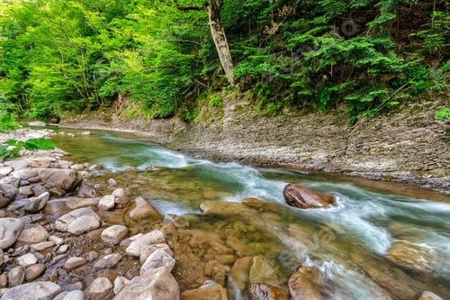 Preview: River With Stones On The Shore In The Forest Near The Mountain Slope. Long Exposure Shot.