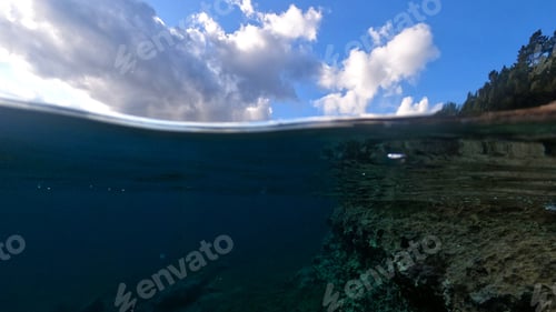 Preview: Beautiful Underwater Split Above And Below Photo Of Rocky Seascape With Deep Blue Sky And Clouds In
