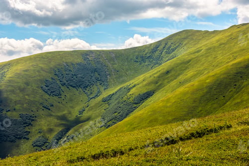 Preview: Green Grass On Hillside Meadow In High Mountains Under The Cloudy Sky