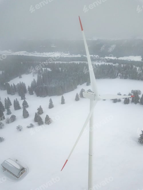 Preview: Aerial View Of Wind Turbine In Snow Covered Landscape In Switzerland. Tall Pylon In Fog, Fir Trees