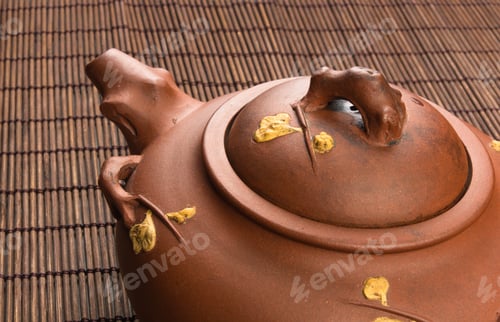 Preview: Brown Chinese Teapot Of Yixing Clay With Traditional Ornament On Bamboo Mat