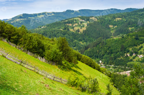 Preview: Wooden Stick Fence In Village In Mountains With Blue Sky, Green Grass And Path In Good Weather Time