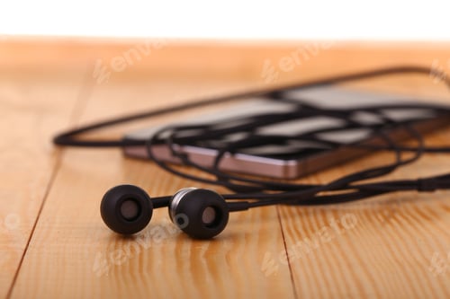 Preview: Mobile Phone With Pair Of Earphone On Wooden Table