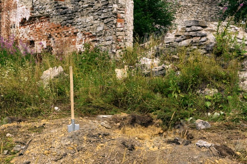 Preview: Search For A Treasure In Ruins - A Shovel Stuck Into The Ground Next To A Dug Pit In The Background