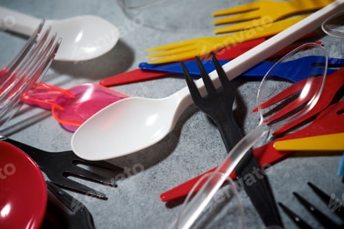 Preview: Multicolored Plastic Cutlery On A Stone Table.