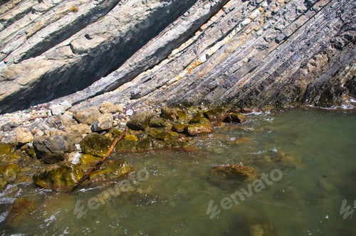 Preview: Rocky Sea Shore With With Seaweed, Transparent Waves With Foam, On A Warm Summer Day