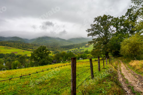 Preview: Road Along The Fence In Rural Outskirts. Pasture Behind The Barbwire. Mountainous Countryside On A