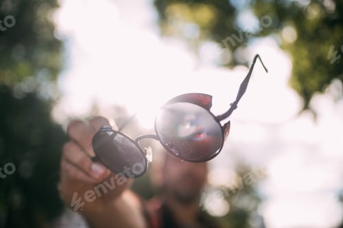 Preview: Close-Up Sunglasses In The Hands Of A Man. The Guy In Defocus Holds Stylish Glasses In His Hands