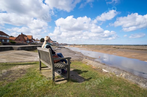 Preview: Woman Sitting On A Bench With A View At Wells Next The Sea, Norfolk, Uk