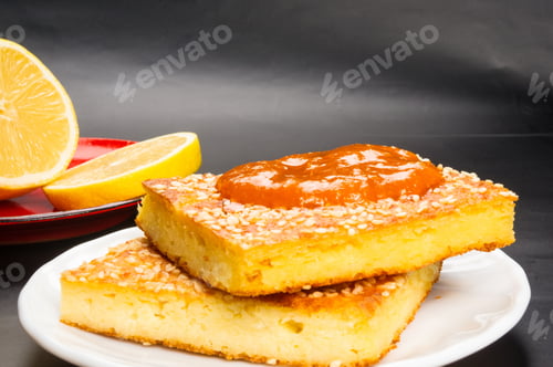 Preview: Slice Of Cheesecake With Sesame Seeds, Apricot Jam And Lemon Slices On A Black Background