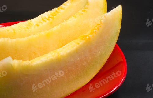 Preview: Slices Of Ripe Juicy Melon In Red Plate On Black Background