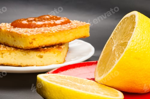Preview: Slice Of Cheesecake With Sesame Seeds, Apricot Jam And Lemon Slices On A Black Background