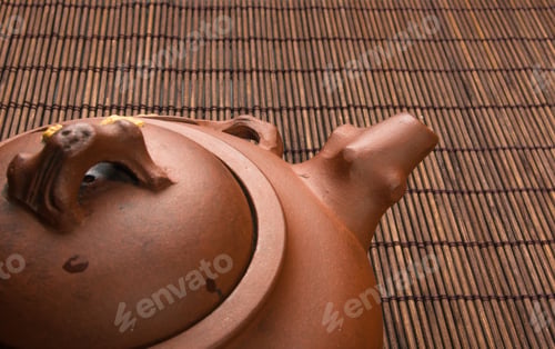 Preview: Brown Chinese Teapot Of Yixing Clay With Traditional Ornament On Bamboo Mat