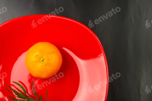 Preview: Tangerine In A Red Plate On Black Background