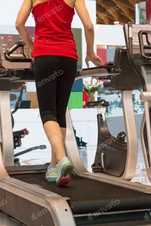 Preview: Athletic Young Woman Exercising On A Running Machine In A Fitness Center
