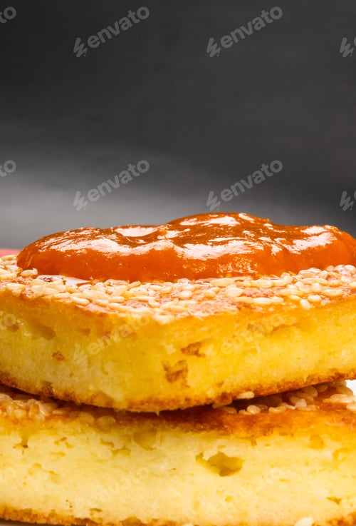 Preview: Slice Of Cheesecake With Sesame Seeds, Apricot Jam And Lemon Slices On A Black Background