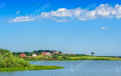 Preview: Lake Near The Field In Picturesque Rural Area On A Serene Summer Day Under Blue Sky With Some Clouds
