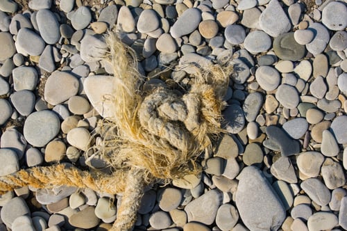 Preview: Old Worn Battered Marine Rope On The Pebble Beach On A Sunny Summer Day, Top View