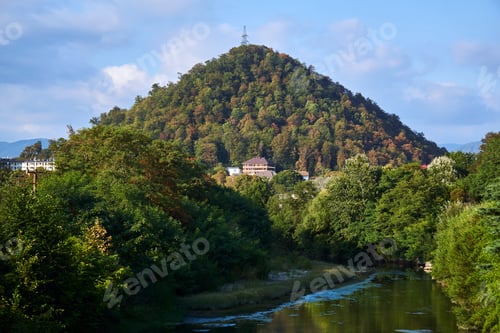Preview: Landscape In A Mountainous Area With A Hill, A River And A Power Transmission Tower At The Top