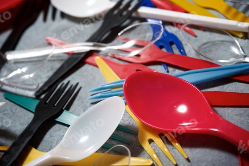 Preview: Multicolored Plastic Cutlery On A Stone Table.