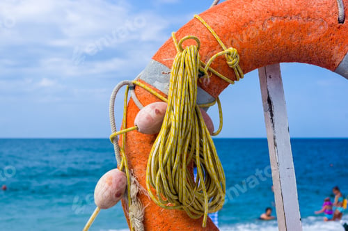 Preview: Orange Emergency Lifebuoy On A Pebbly Sea Beach, Close Up